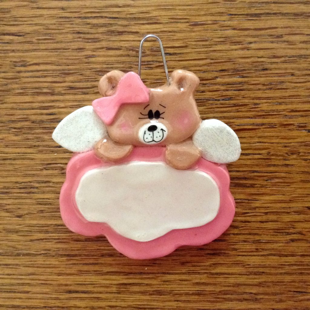 A pink bear ornament with wings and a bow.