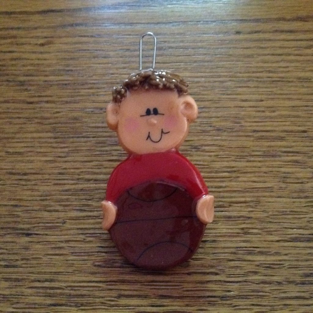 A small clay figure of a boy holding a frisbee.
