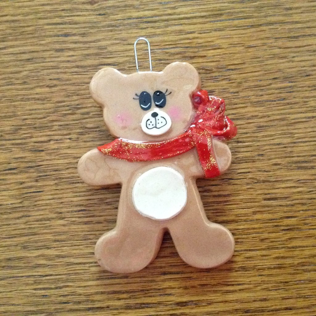 A teddy bear ornament is sitting on the table.