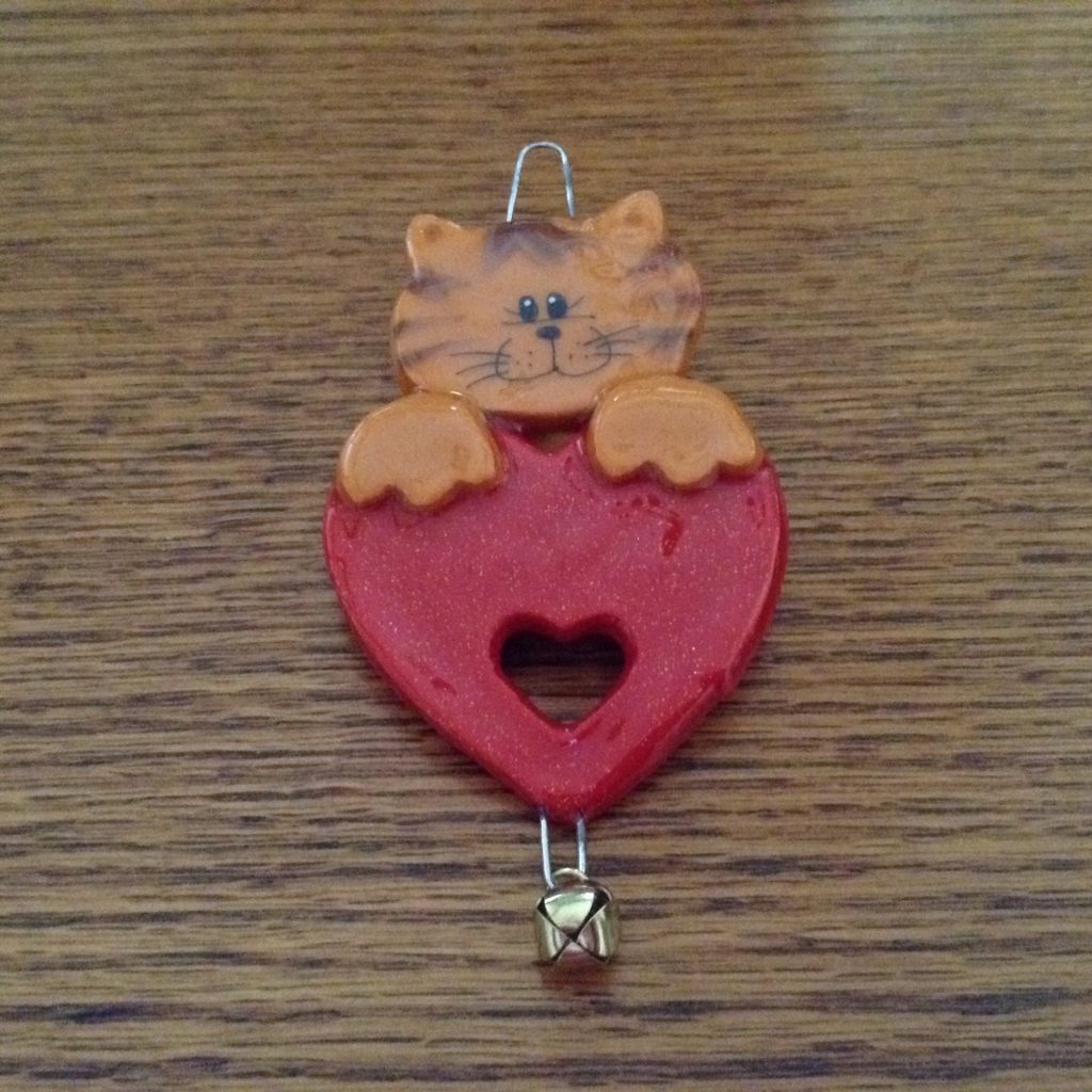 A cat is hanging on the side of a heart.