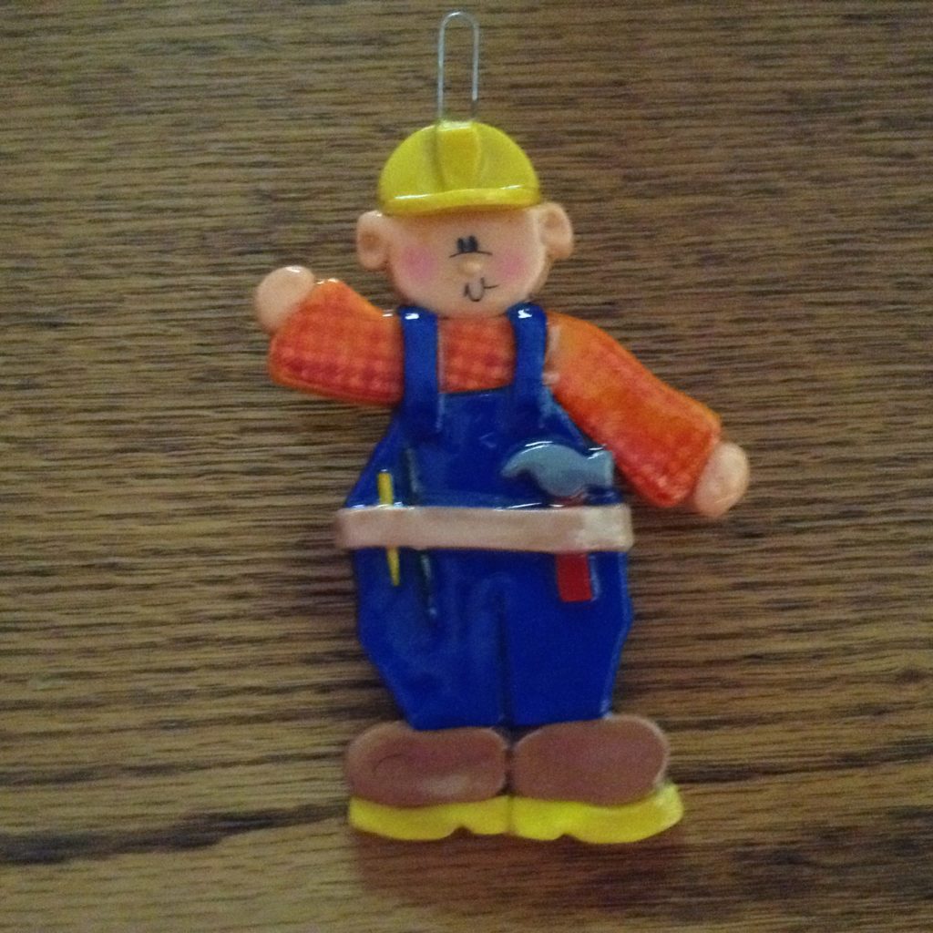 A toy bear with tools on it's head and arms.
