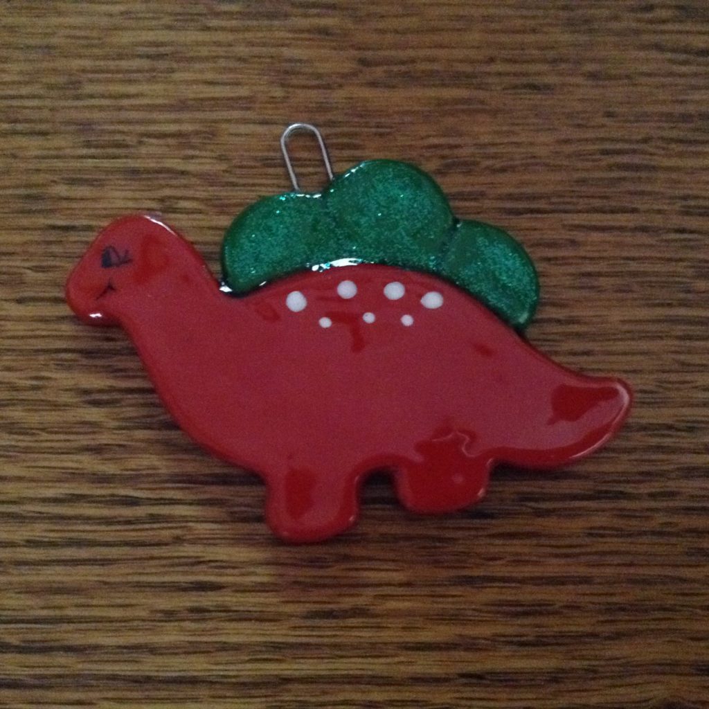 A red dinosaur ornament sitting on top of a wooden table.