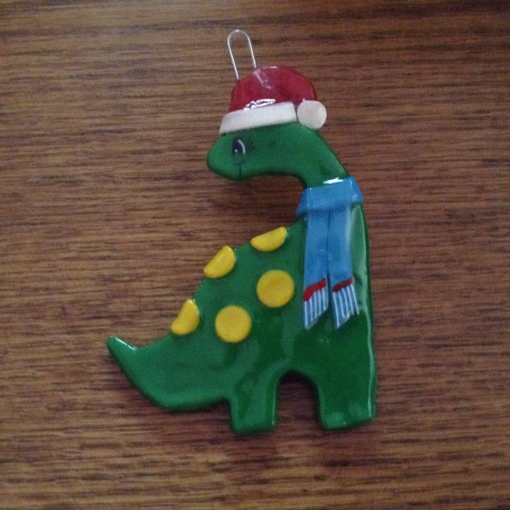 A green dinosaur with a hat and scarf on it's head.