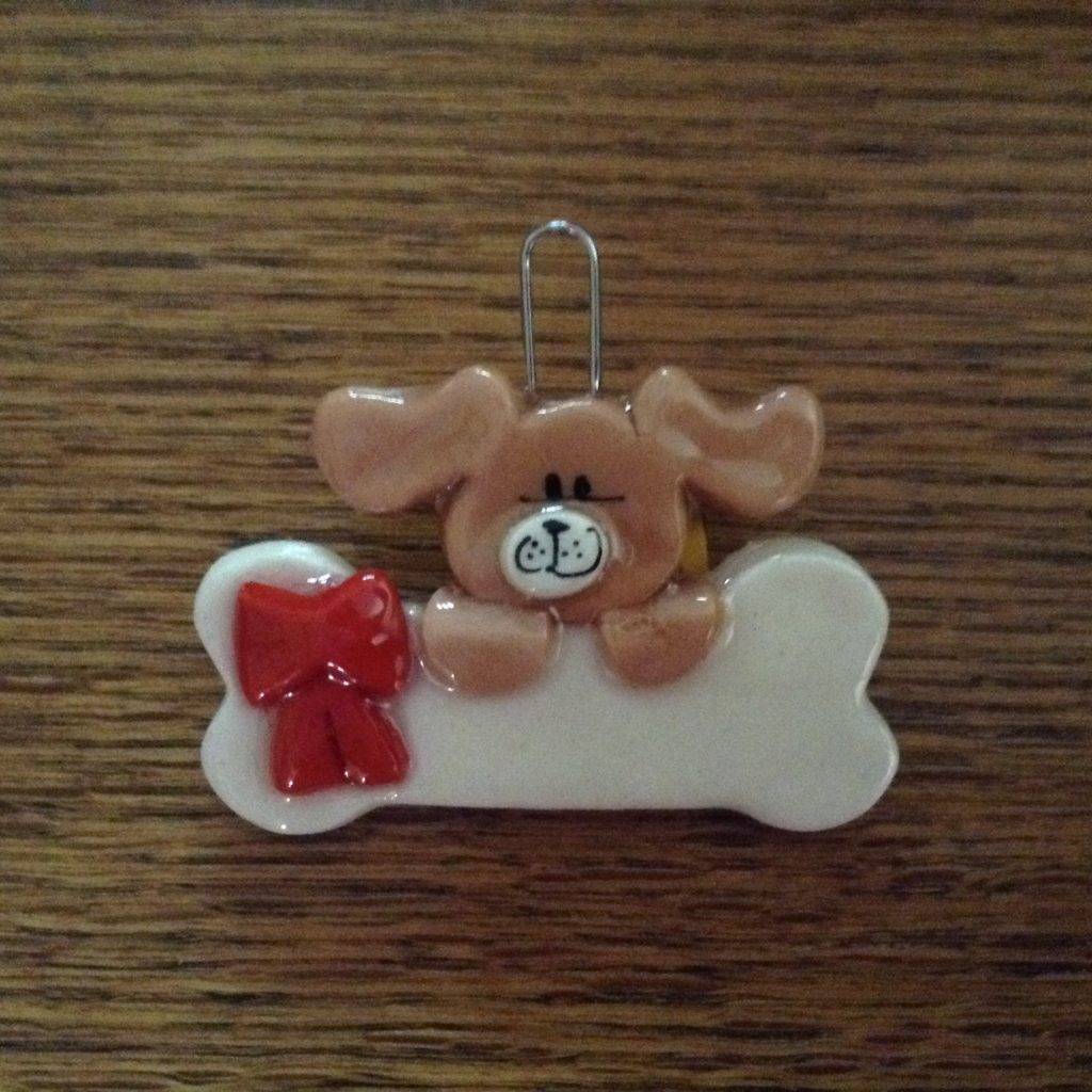 A dog ornament sitting on top of a bone.
