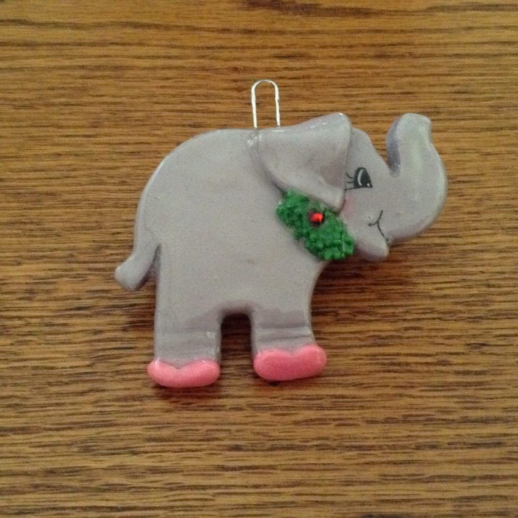 A gray elephant ornament with pink feet and green nose.