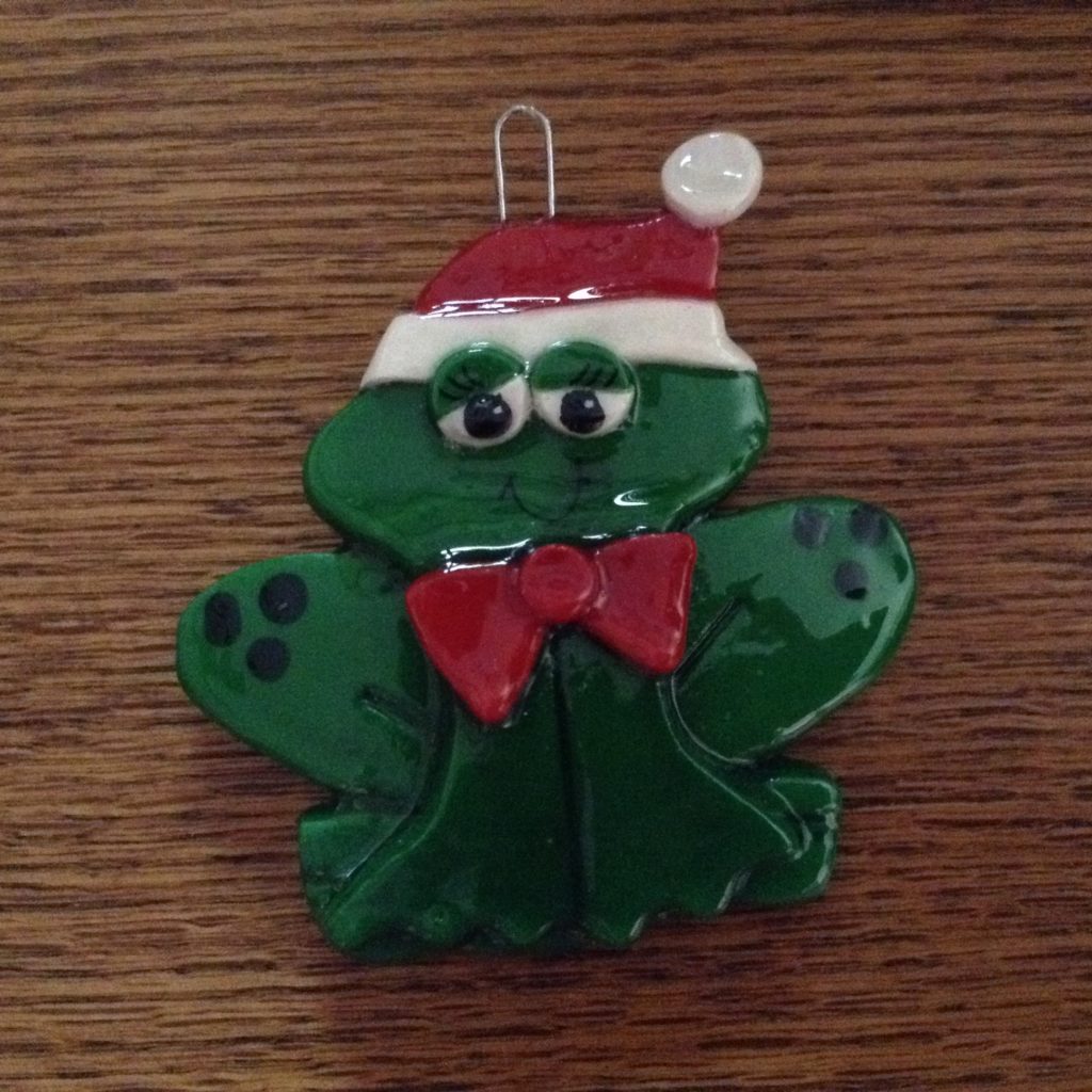 A green frog with a red bow tie and santa hat.