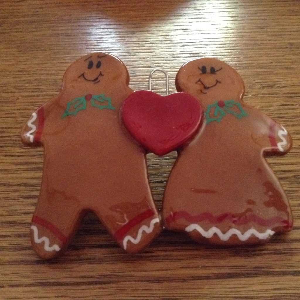 Two gingerbread men holding a heart on top of a table.
