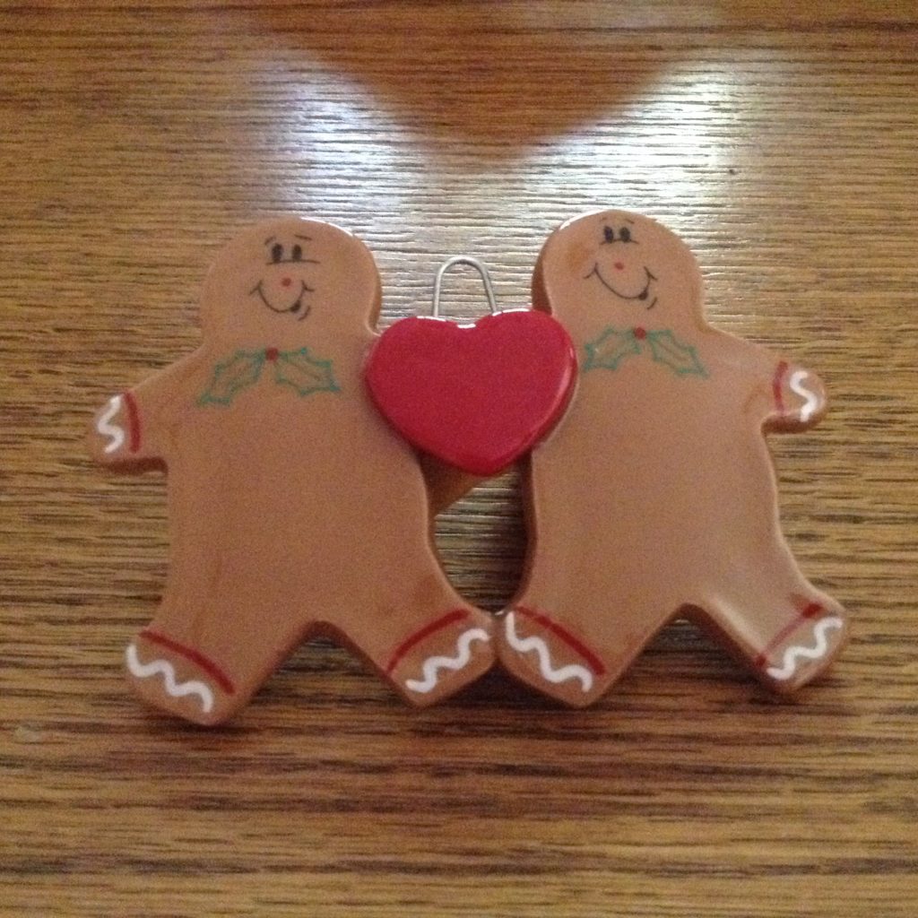 Two gingerbread men holding hands with a heart.