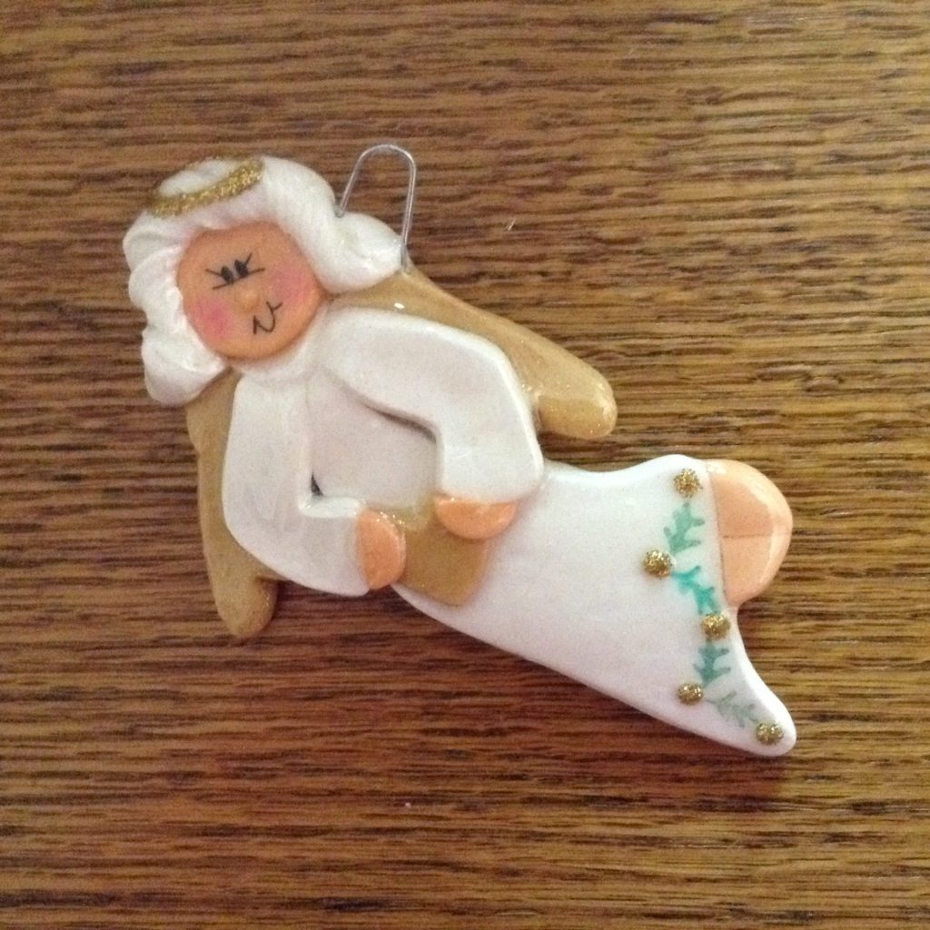 A white angel ornament sitting on top of a wooden table.