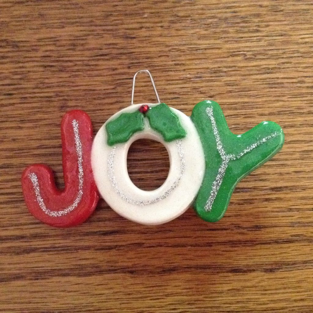 A red and green ornament that says joy.