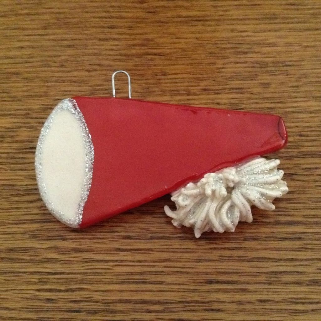 A red and white piece of paper with a pom-poms on it.