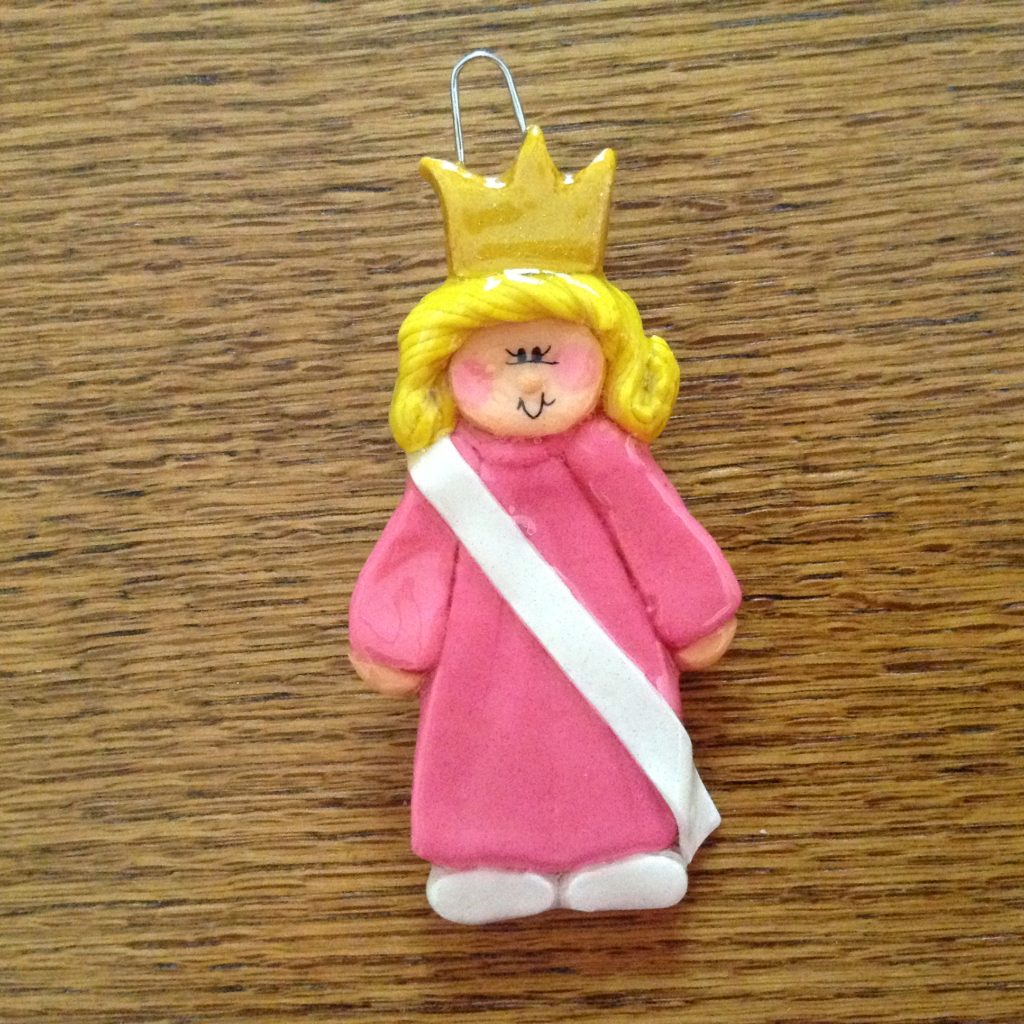 A pink princess ornament with a crown on it.