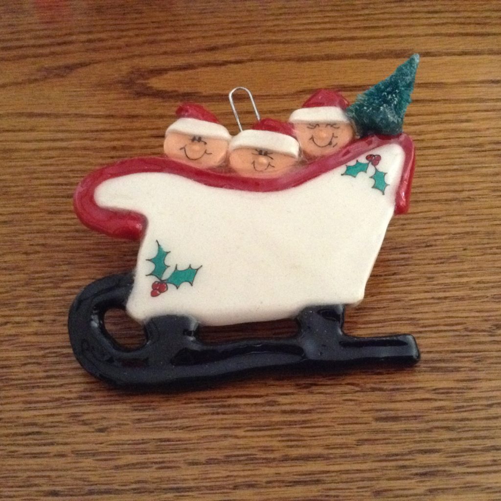 A christmas ornament with three people in the sled.