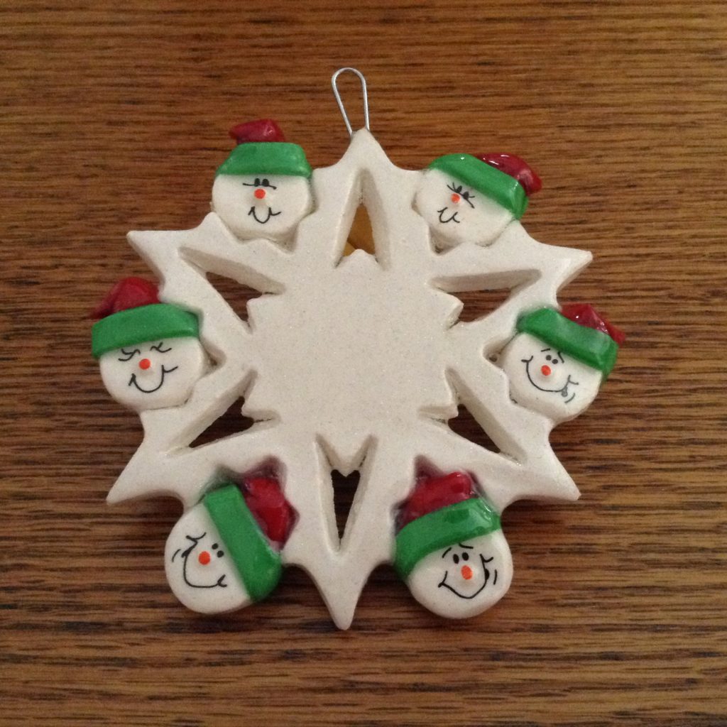 A white snowflake ornament with faces of snowmen.