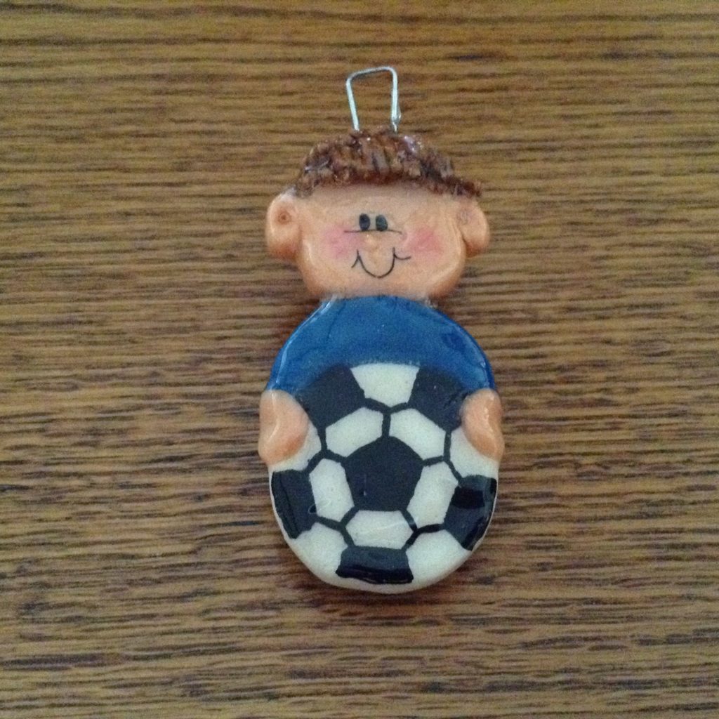 A small clay figure of a boy holding a soccer ball.