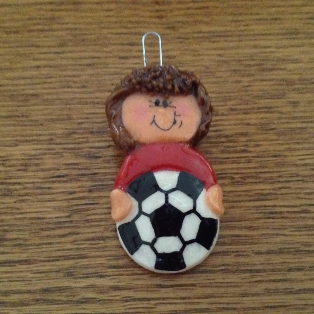 A small clay figure holding a soccer ball.