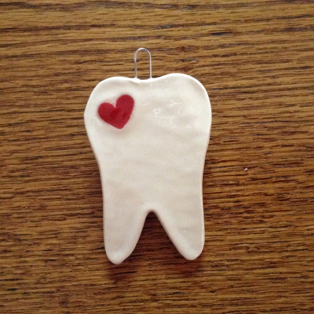 A tooth shaped ornament with a heart on it.