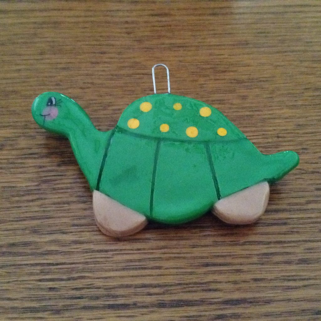 A green turtle cookie sitting on top of a wooden table.