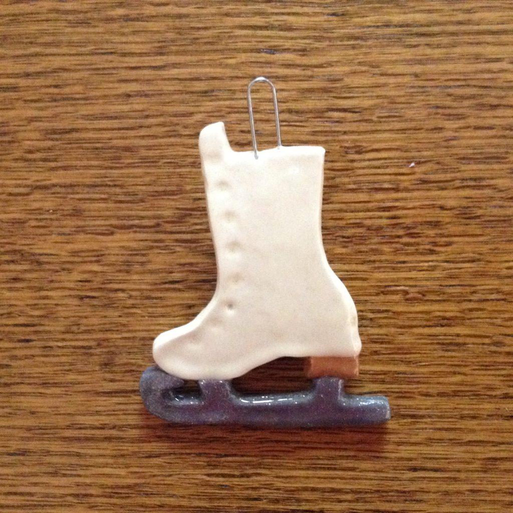 A white ice skate ornament sitting on top of a wooden table.