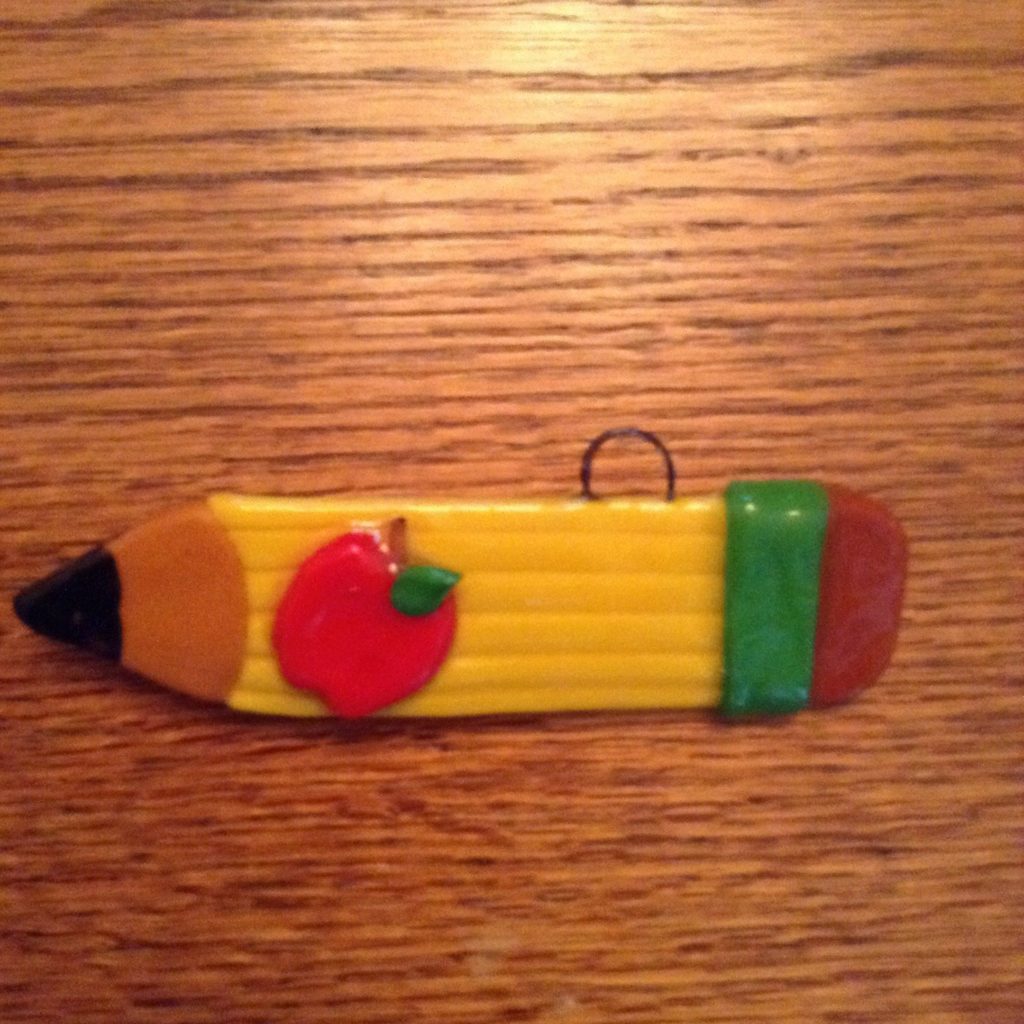A pencil with an apple on it.