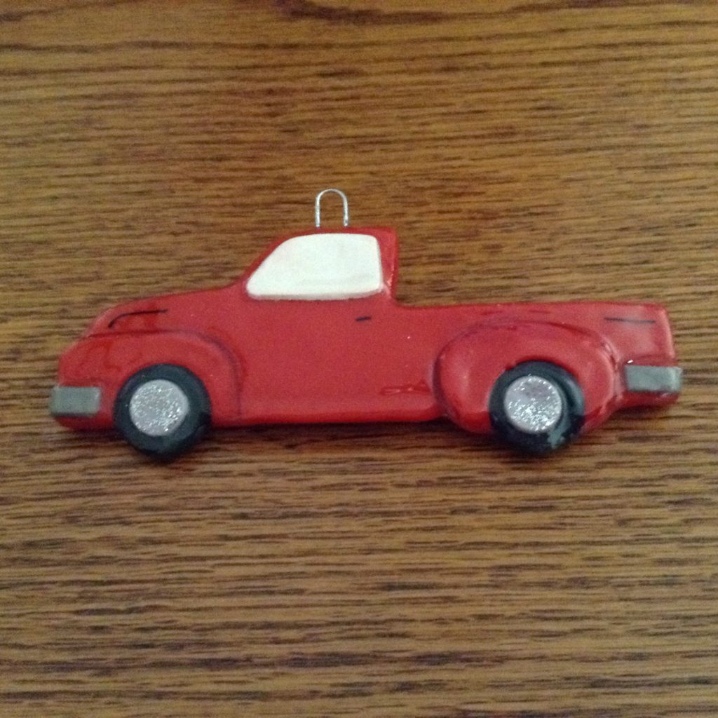 A red truck ornament sitting on top of a wooden table.