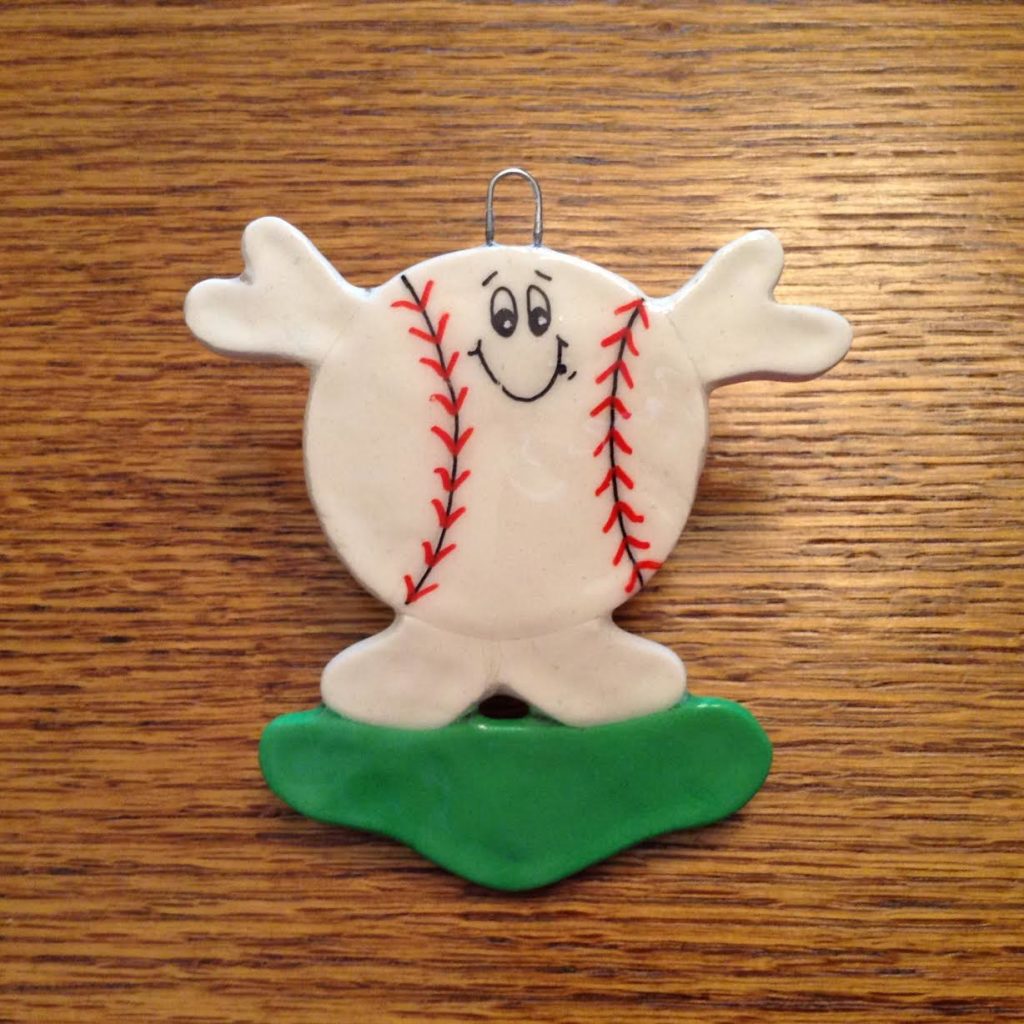 A baseball is sitting on the ground with his arms spread out.
