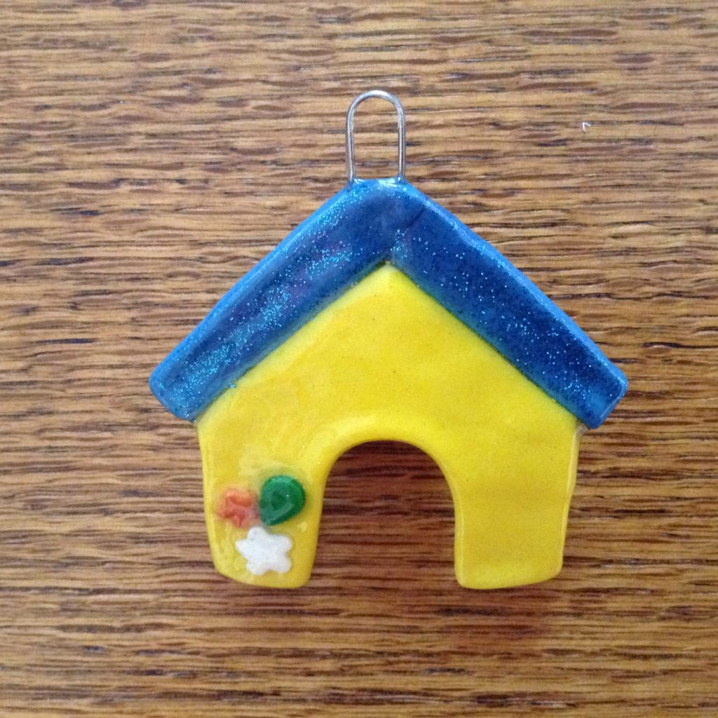A yellow and blue house ornament on top of a wooden table.