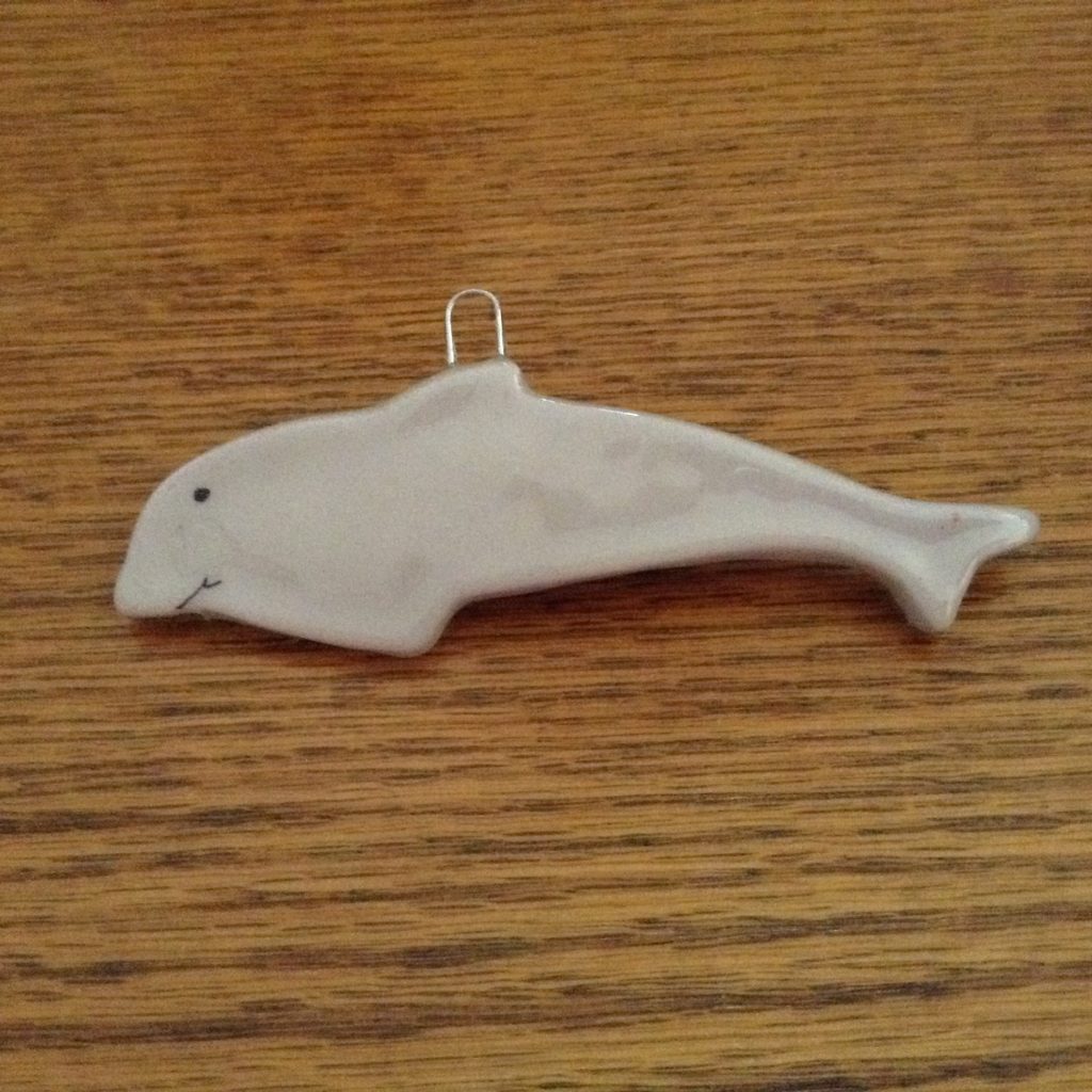 A white dolphin ornament sitting on top of a wooden table.