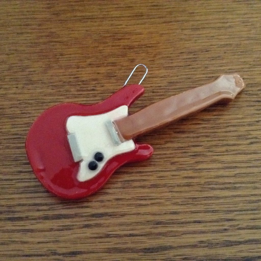 A red guitar is sitting on the table.