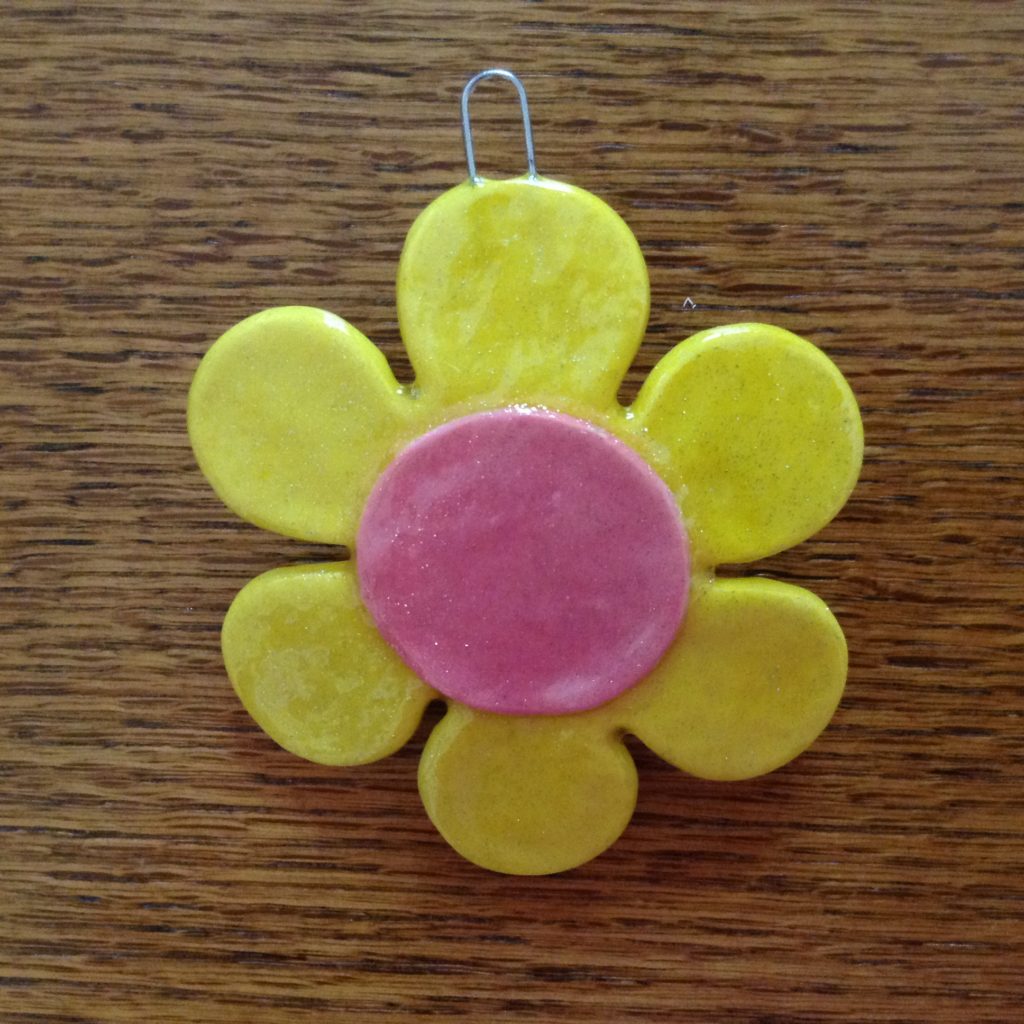 A yellow and pink flower on top of a wooden table.
