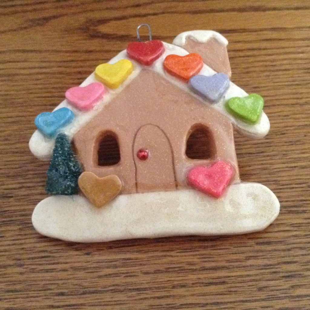 A gingerbread house ornament with hearts on it.