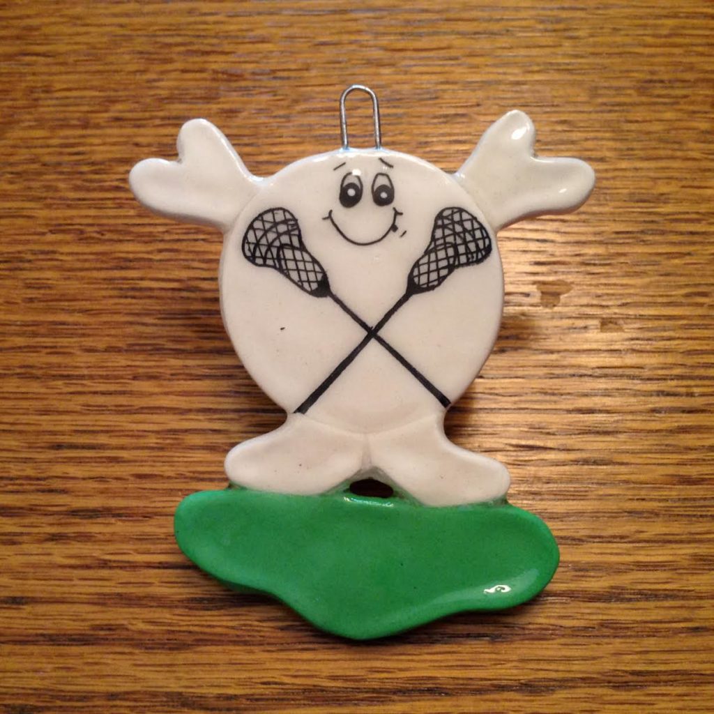 A white ceramic ornament with two lacrosse sticks on it.