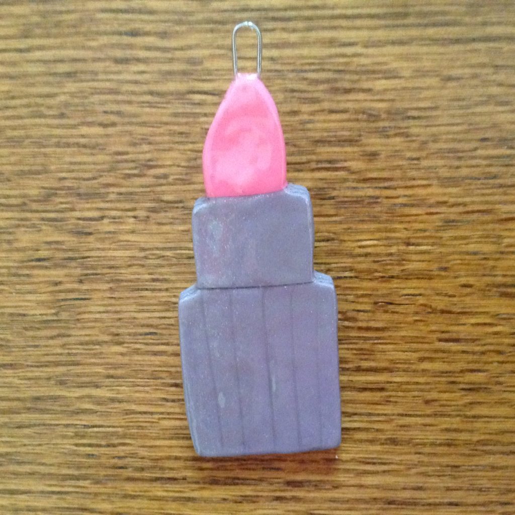 A purple lipstick with pink top on wooden table.