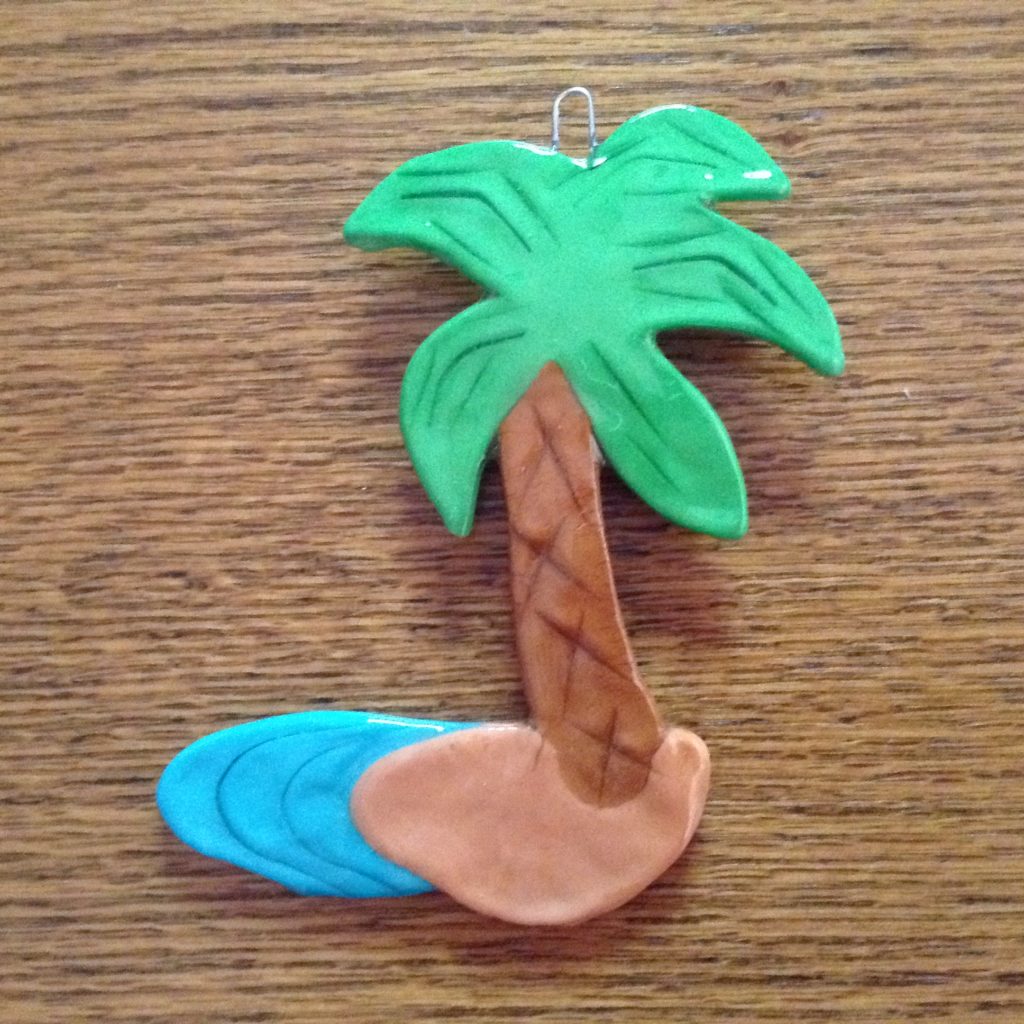 A palm tree and surfboard made out of clay.