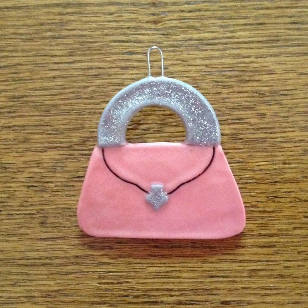 A pink purse ornament sitting on top of a wooden table.