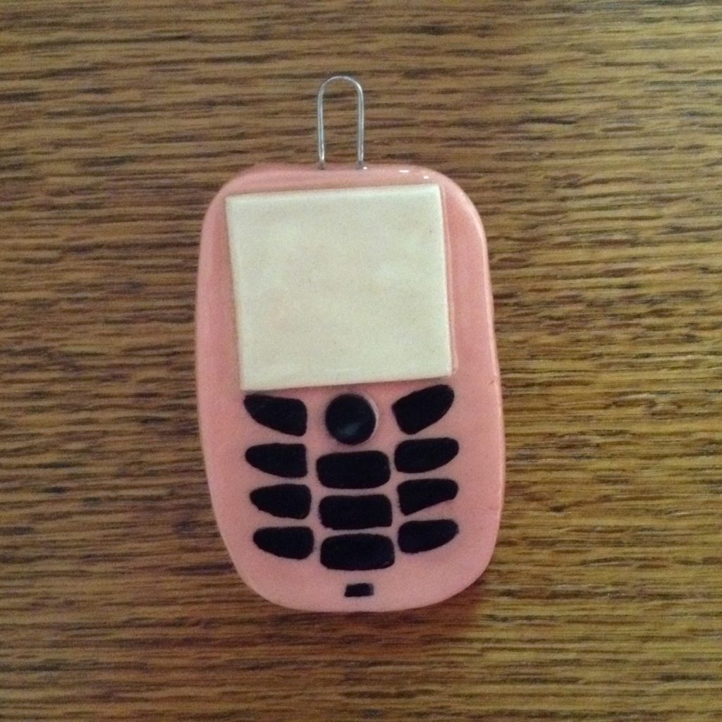 A pink cell phone sitting on top of a wooden table.