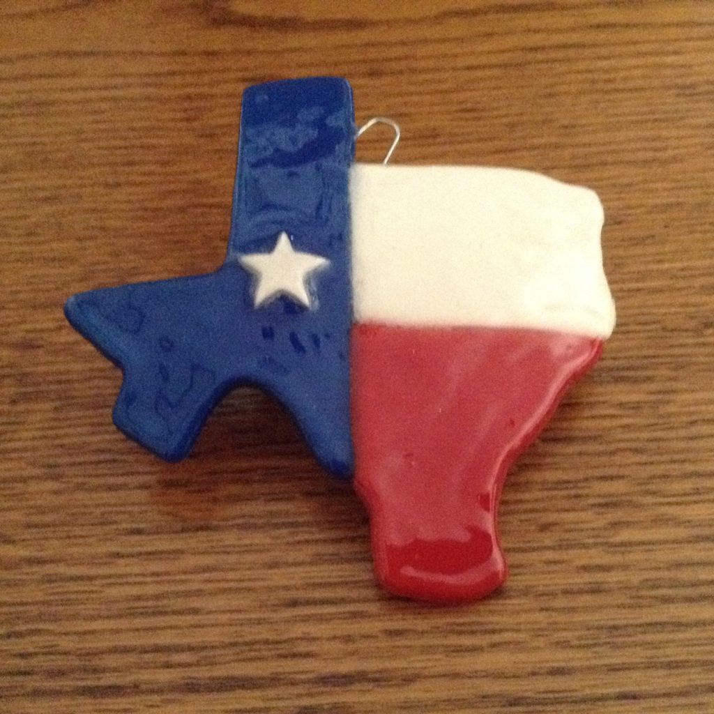 A texas shaped ornament is sitting on the table.