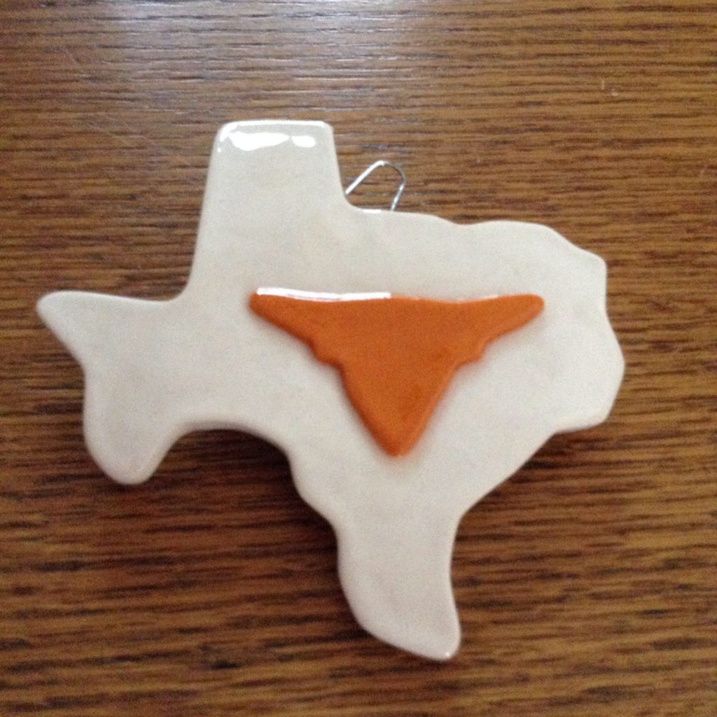 A white texas shaped ornament with an orange state.