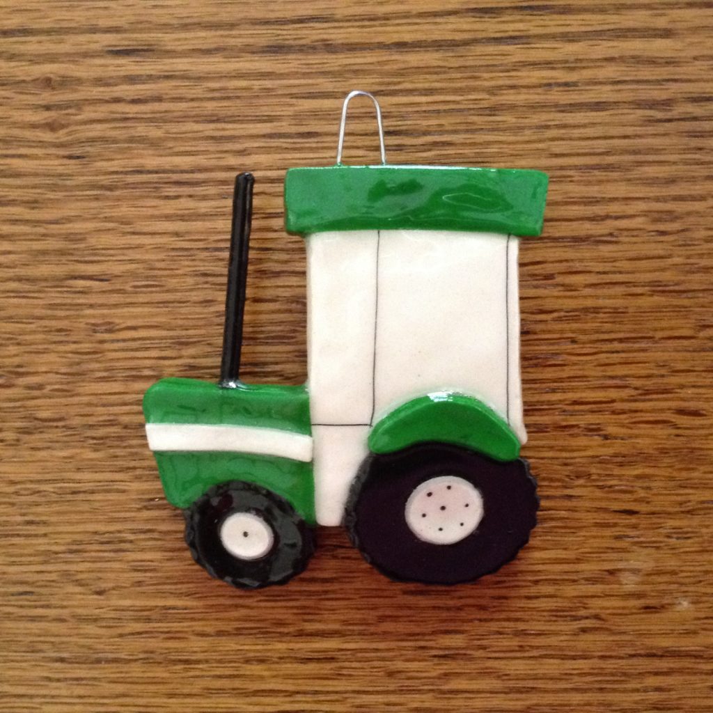 A green and white tractor ornament on top of a wooden table.