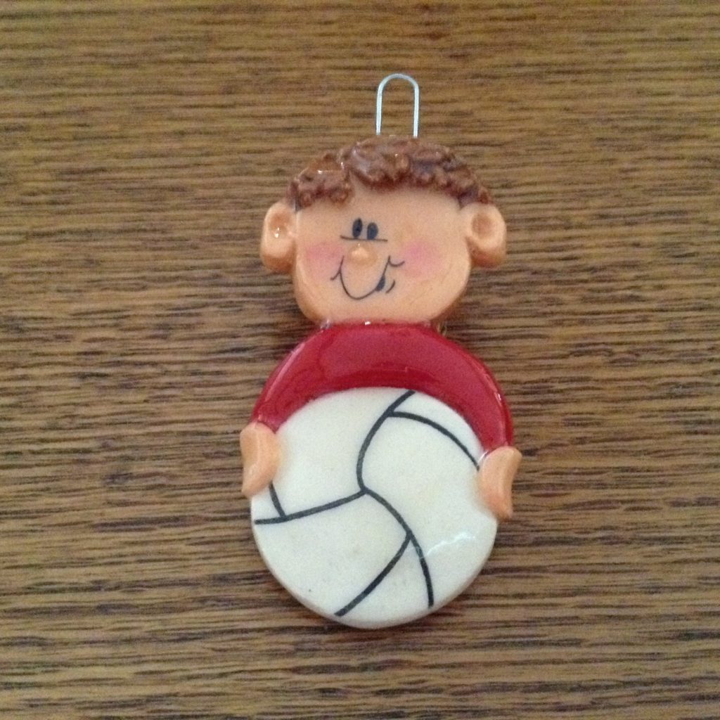 A clay figure of a boy holding a volleyball.