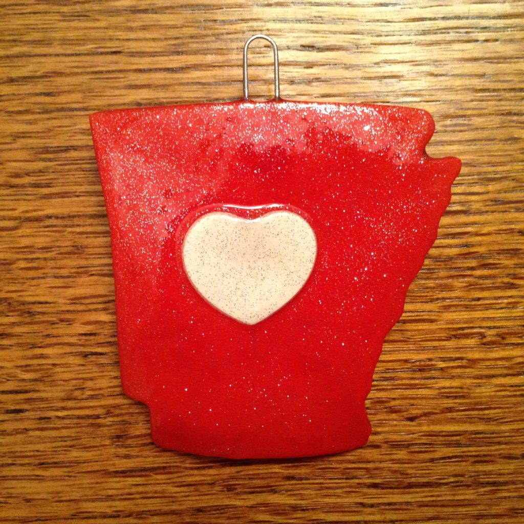 A red and white heart shaped ornament on top of a wooden table.