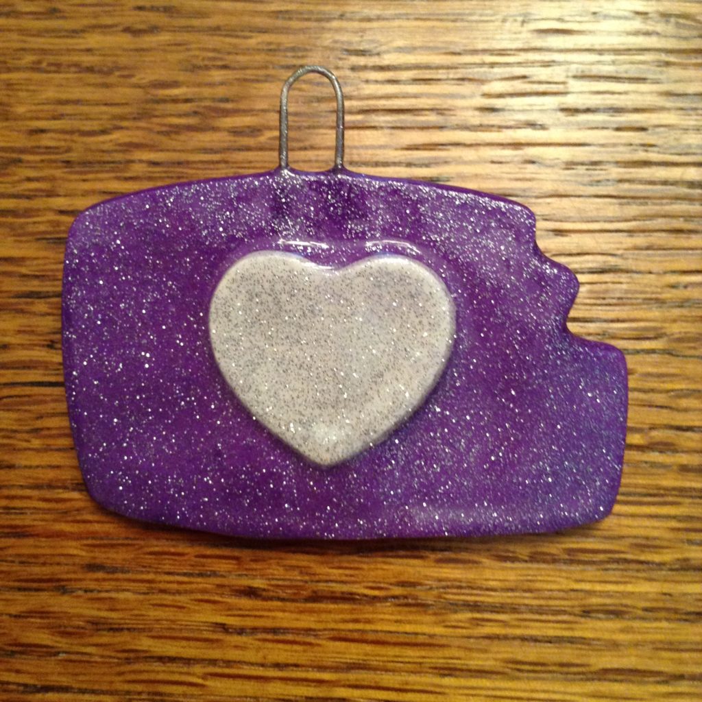 A purple and white heart ornament on top of a wooden table.