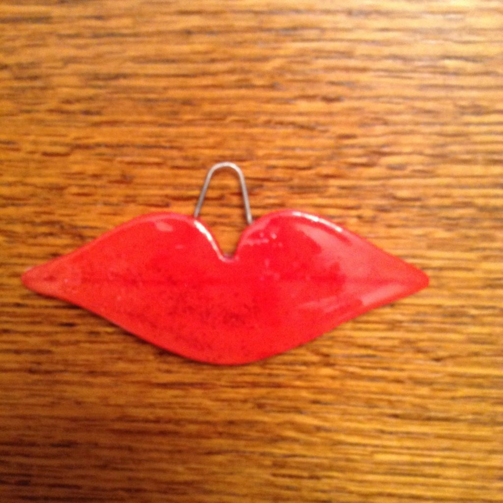 A red lip shaped object hanging on the wall.