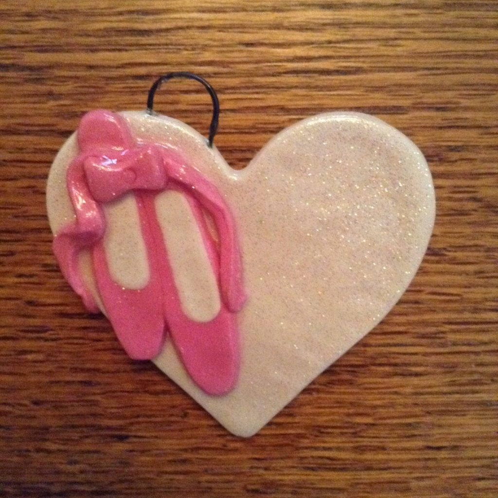 A heart shaped ornament with pink ballet shoes on it.