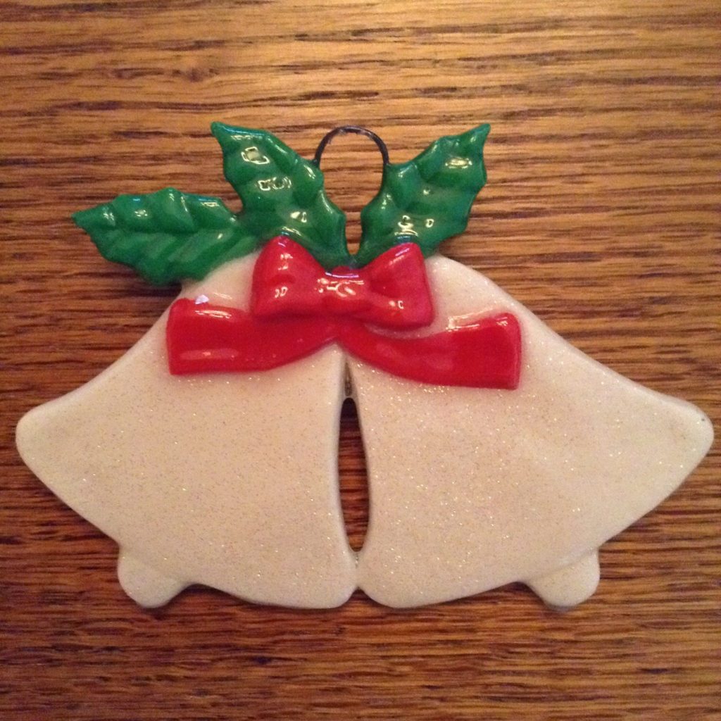 A white bell ornament with red bow on top.