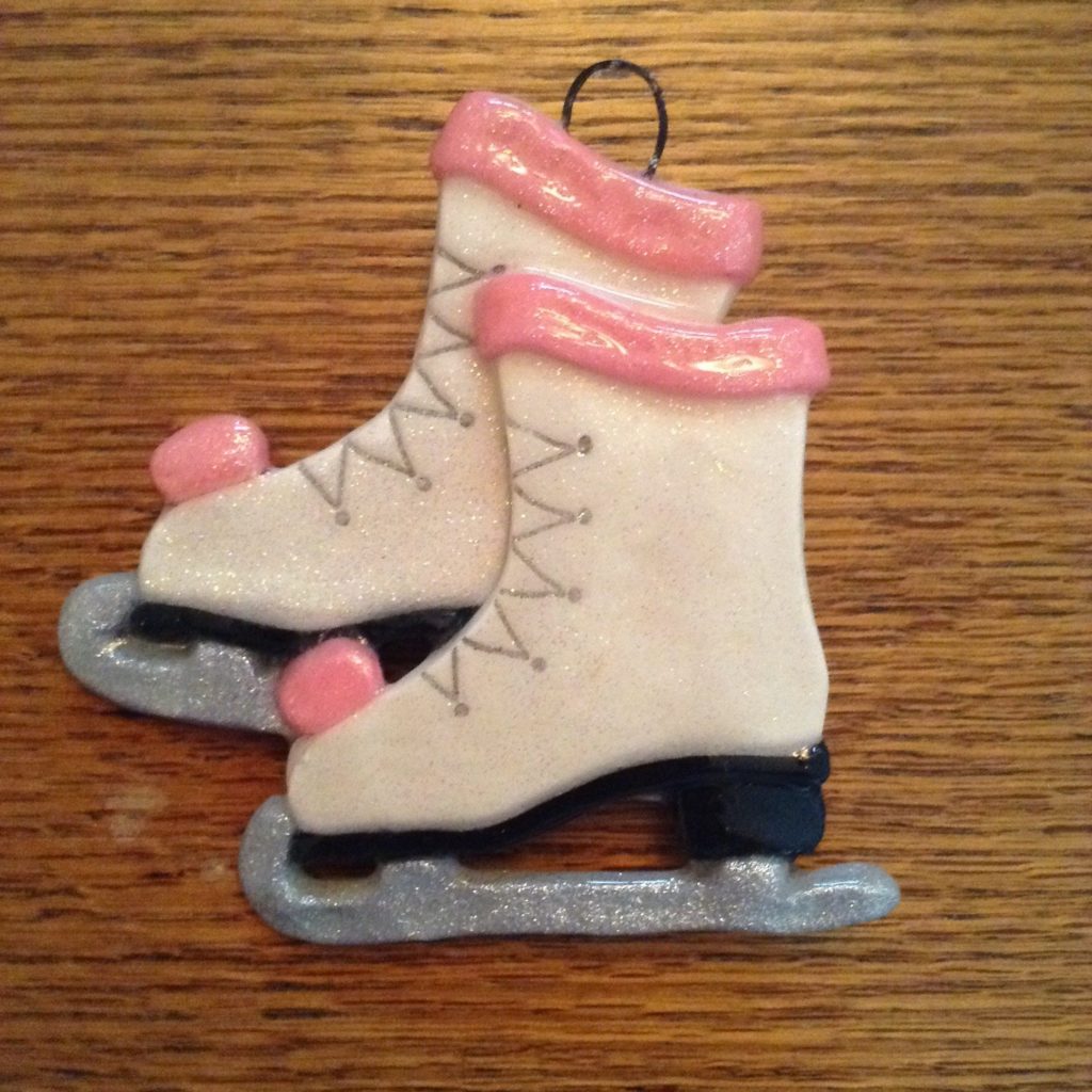 A pair of white ice skates with pink trim.