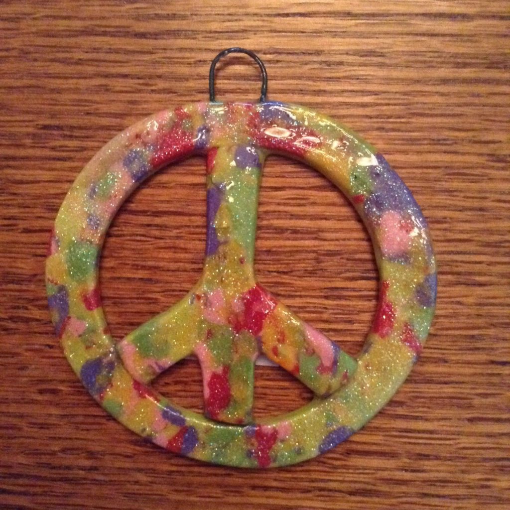 A peace sign ornament is painted with paint.