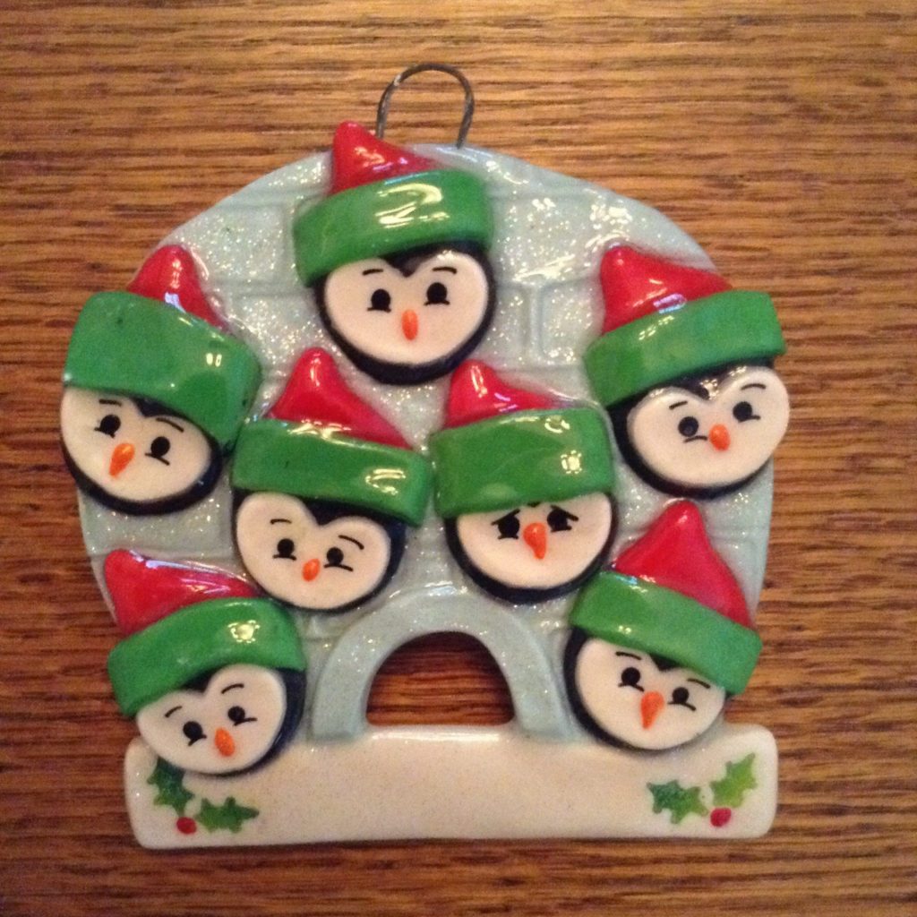A christmas ornament with penguins wearing hats.