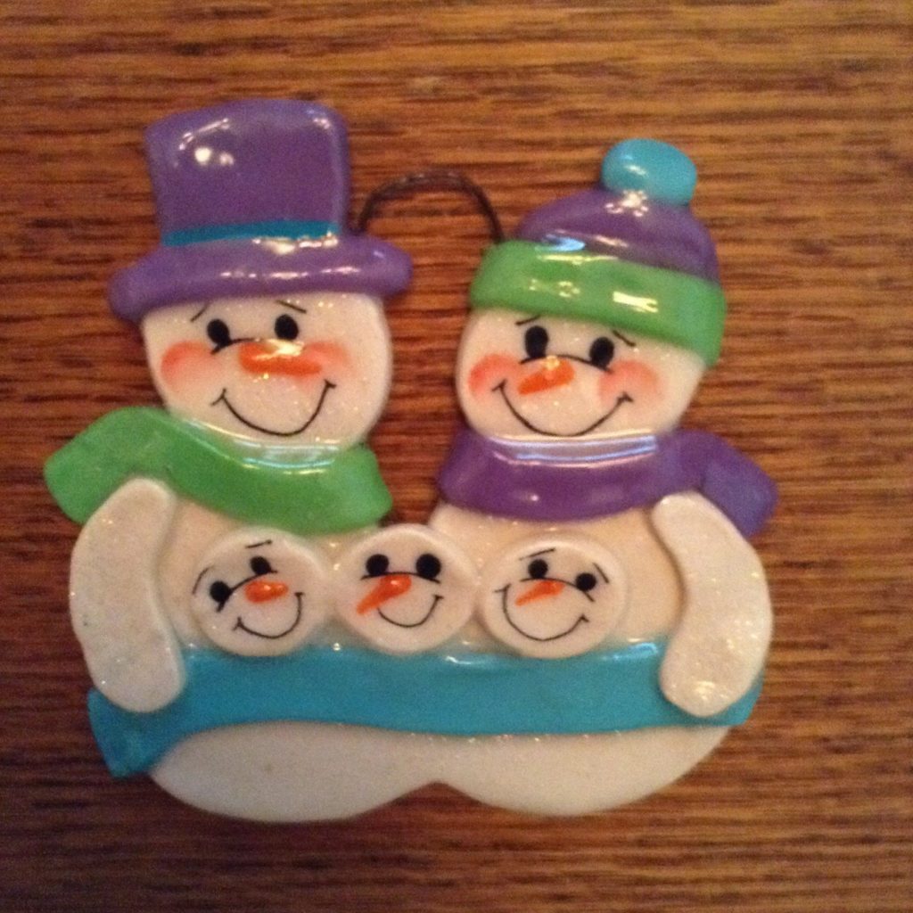 A christmas ornament of three snowmen on a table.