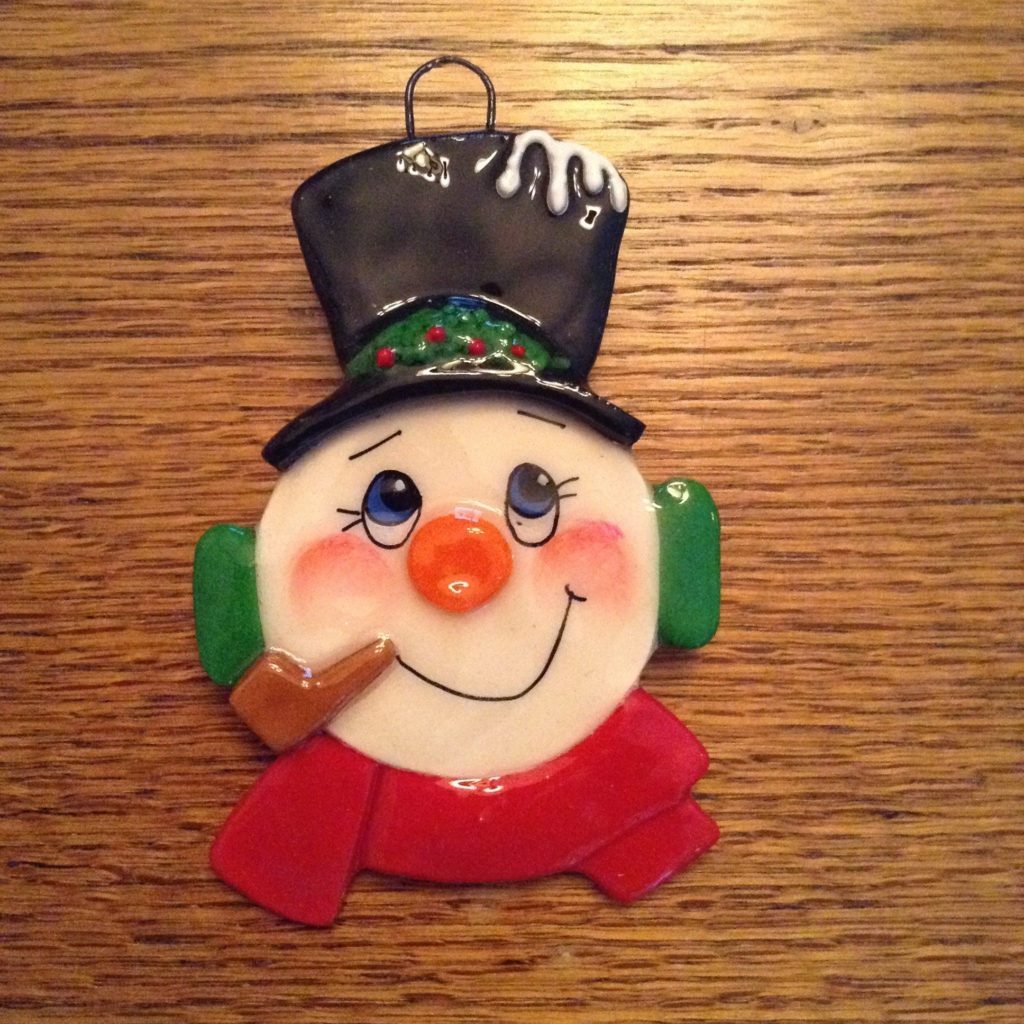 A snowman ornament with a cigar in its mouth.